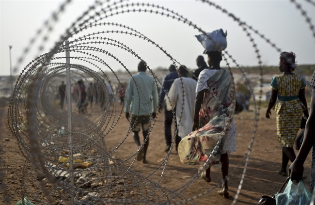 ,displaced people walk next to a razor wire fence at the United Nations base in the capital Juba, South Sudan on Jan. 19, 2016.