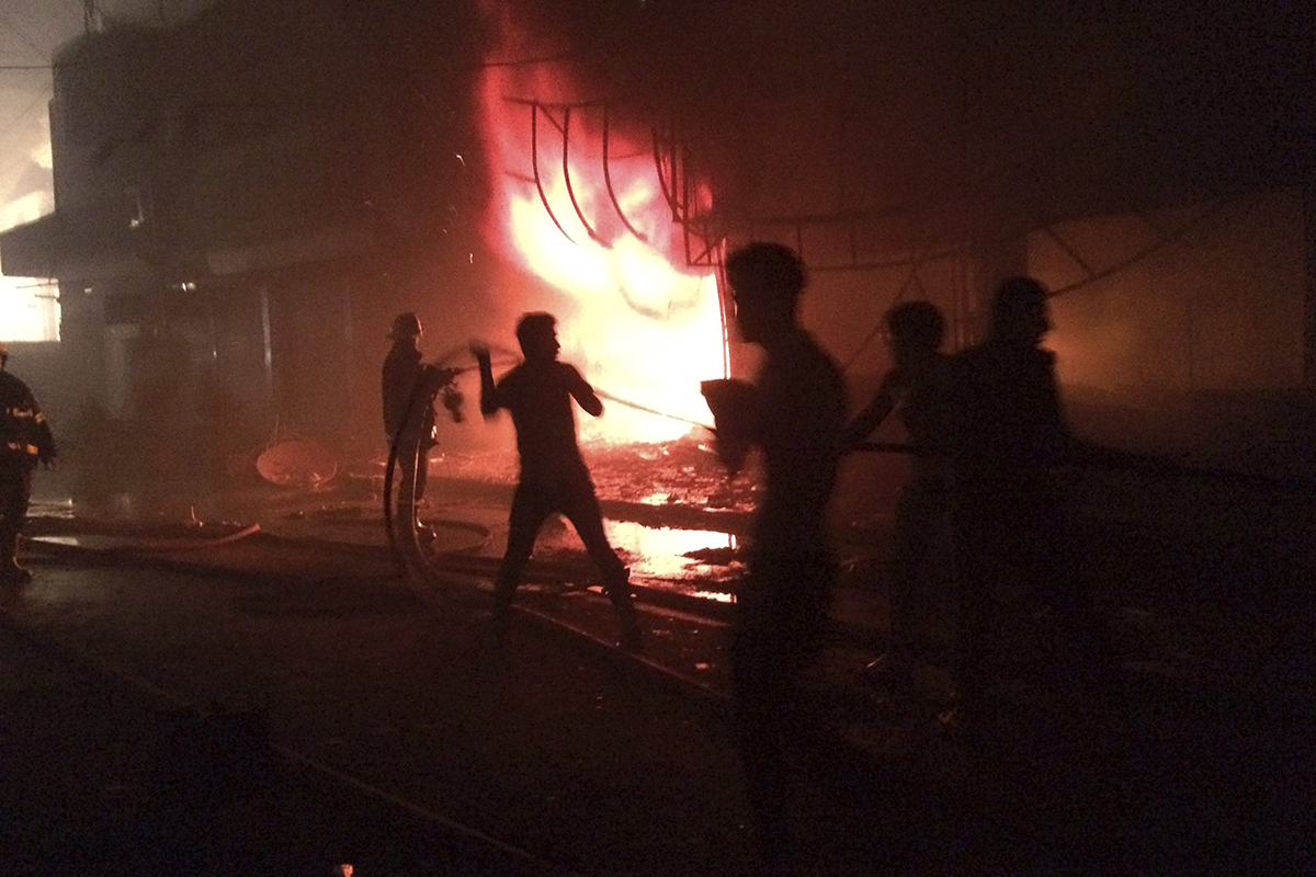 Iraqi firefighters extinguish a fire as civilians gather after a car bomb at a commercial area in Karada neighborhood, Baghdad, Iraq, early Sunday, July 3, 2016. 