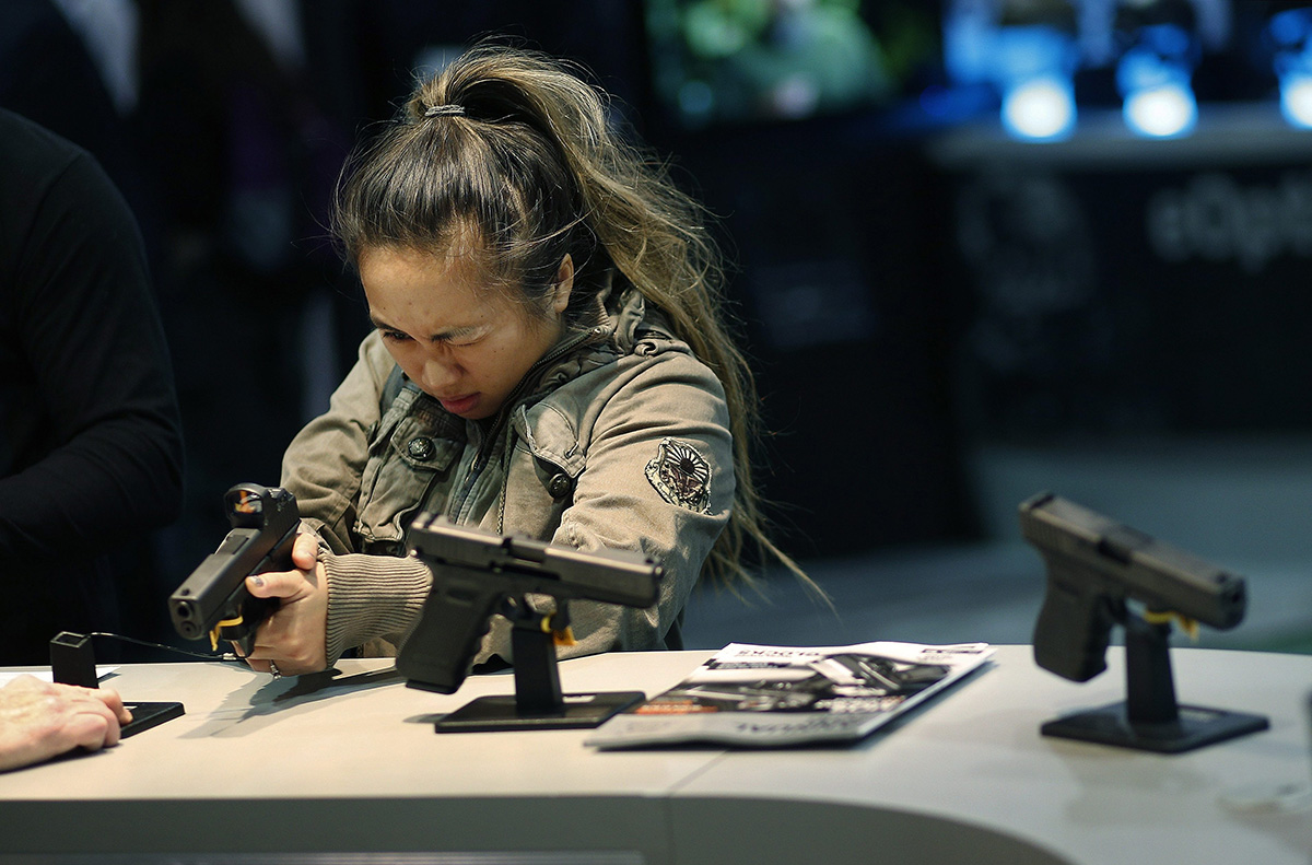 In this Jan. 19, 2016 file photo, a woman looks at a handgun at the Glock booth at the Shooting Hunting and Outdoor Trade Show in Las Vegas.
