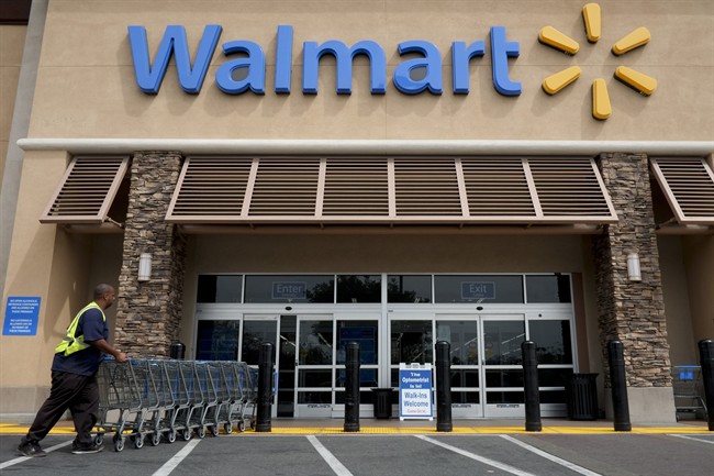 In this May 9, 2013, file photo, a worker pushes shopping carts in front of a Wal-Mart store in La Habra, Calif. 