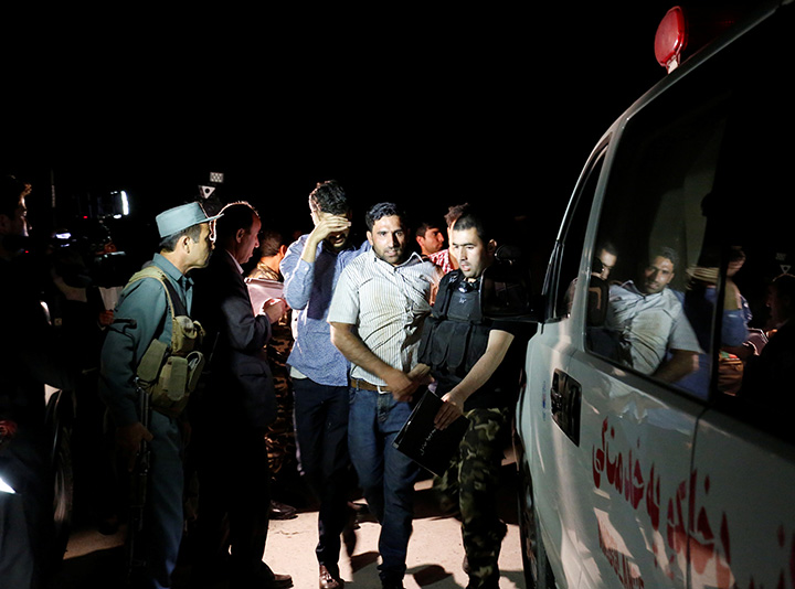 Men walk towards an ambulance after they were rescued from the site of an attack at American University of Afghanistan in Kabul, August 24, 2016.