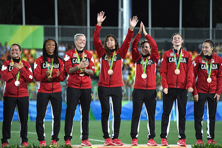 Members of Canada’s women’s rugby sevens team wave to fans during the medal ceremony after winning the bronze medal against Great Britain at the 2016 Olympic Games in Rio de Janeiro, Brazil on Monday, Aug. 8, 2016.