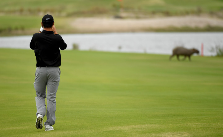 Danny Lee of New Zealand takes a photo of a capybara