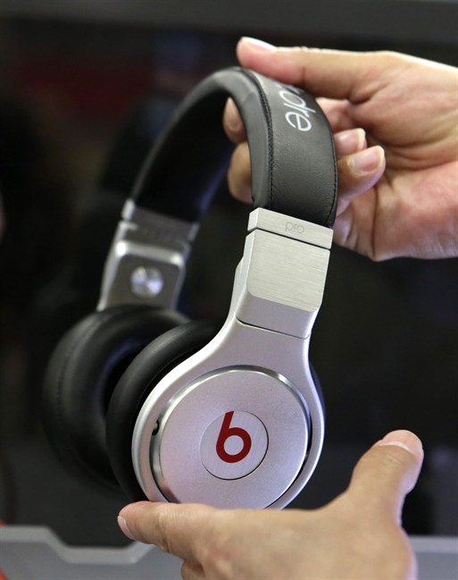 In this Thursday, May 29, 2014, file photo, a customer holds a pair of Beats headphones at a Best Buy store in Hialeah, Fla.