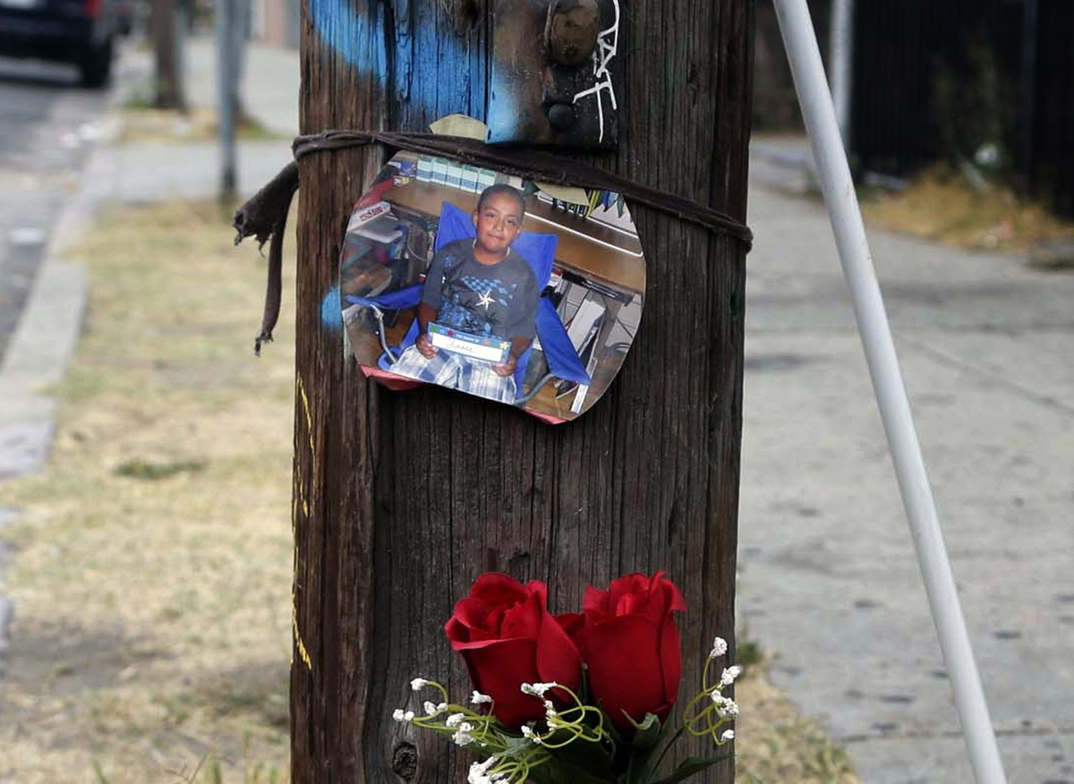 A photo and flowers are left at a street side memorial for a teen who was fatally shot by police in the Boyle Heights section of Los Angeles on Wednesday, Aug. 10, 2016. 