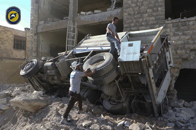 In this photo provided by the Syrian Civil Defense group known as the White Helmets, rescue workers remove a destroyed ambulance after airstrikes in Ansari neighborhood in the rebel-held part of eastern Aleppo. Friday, Sept. 23, 2016.