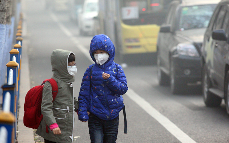 Two children wearing face masks walk in heavy smog on November 3, 2015 in Harbin, Heilongjiang Province of China. 