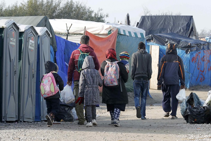 Migrants carry their belongings as they walk in an alley near tents and makeshift shelters on the eve of the evacuation and dismantlement of the camp called the “Jungle” in Calais, France, October 23, 2016. REUTERS/Philippe Wojazer