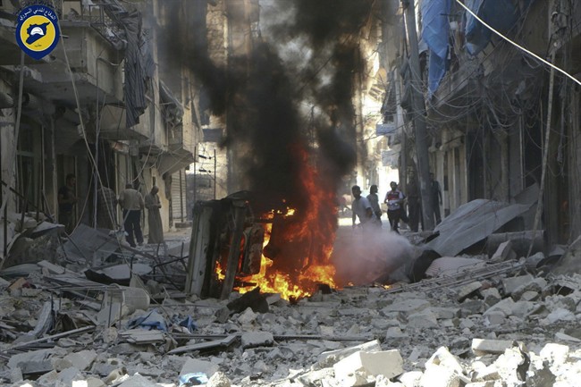 In this photo provided by the Syrian Civil Defense group known as the White Helmets, Syrians inspect damaged buildings after airstrikes by government helicopters on the rebel-held Aleppo neighbourhood of Mashhad, Syria, Tuesday Sept. 27, 2016. 
