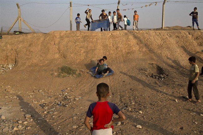 Children use a piece of plastic to slide down a slope at the Baharka camp for displaced persons on the outskirts of Irbil, Iraq, Tuesday, Oct. 25, 2016. Nearby Mosul, the largest city controlled by the Islamic State group, is still home to more than 1 million civilians. (AP Photo/Marko Drobnjakovic).