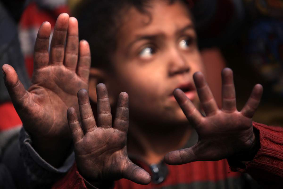 Children reacts to the cameras while their hands are covered by a layer of grime from an oil facility that Islamic State torched in Qayyara, Iraq, November 12, 2016.