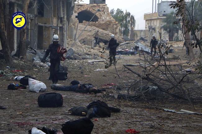This photo provided by the Syrian Civil Defense White Helmets, which has been authenticated based on its contents and other AP reporting, shows workers pass by bodies after artillery fire struck the Jub al-Quba district in Aleppo, Syria, Wednesday, Nov. 30, 2016.
