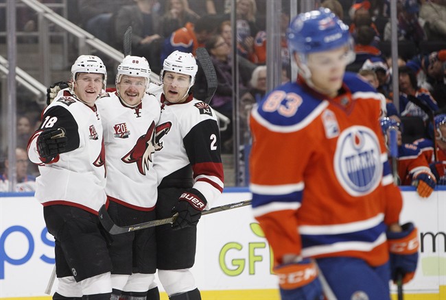 Arizona Coyotes' Christian Dvorak (18), Jamie McGinn (88) and Luke Schenn (2) celebrate a goal as Edmonton Oilers' Matthew Benning (83) skates past during third period NHL action in Edmonton, Alta., on Sunday November 27, 2016.
