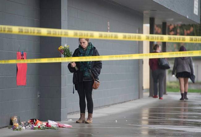 A girl arrives to lay flowers at a makeshift memorial outside Abbotsford Secondary School in in Abbotsford, B.C., Wednesday, Nov. 2, 2016. Two students were stabbed at the school Tuesday, leaving one dead and one in hospital. THE CANADIAN PRESS/Jonathan Hayward.