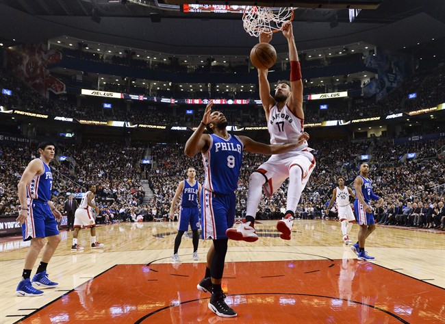 Toronto Raptors centre Jonas Valanciunas (17) slam dunks the ball past Philadelphia 76ers centre Jahlil Okafor (8) during first half NBA basketball action in Toronto on Monday, November 28, 2016. THE CANADIAN PRESS/Nathan Denette.