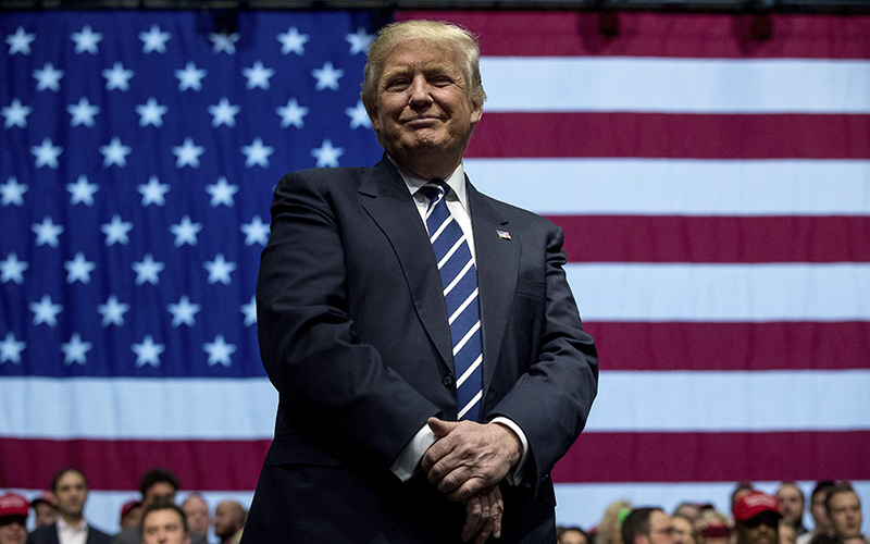 President-elect Donald Trump smiles as he listens to his pick for Education Secretary Betsy DeVos speak during a rally at DeltaPlex Arena, Friday, Dec. 9, 2016, in Grand Rapids, Mich. 