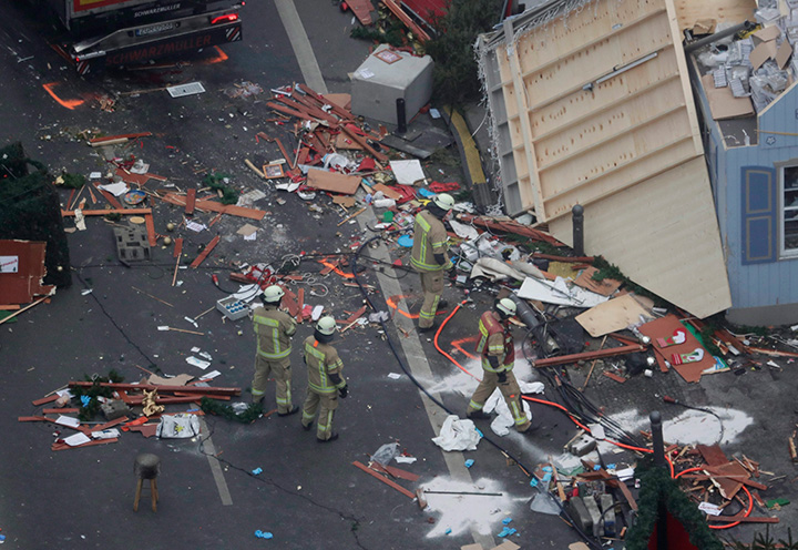 Firefighters look at the debris after the trailer has been towed away from the crime scene in Berlin, Germany, Tuesday, Dec. 20, 2016, the day after a truck plowed into a crowded Christmas market, killing several people.