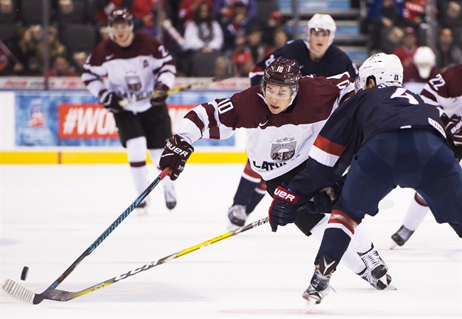 Latvia's Martins Dzierkals (10) drives past the United States' Caleb Jones (4) during third period IIHF World Junior Championships in Toronto on Monday, December 26, 2016. THE CANADIAN PRESS/Nathan Denette.