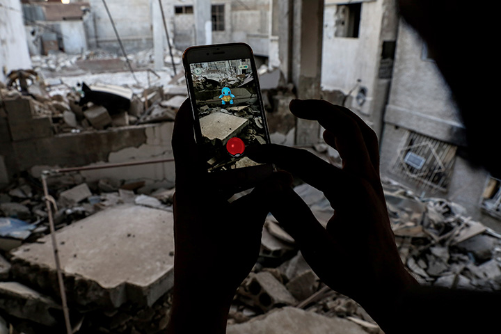 A Syrian gamer uses the Pokemon Go app on his mobile phone to catch a Pokemon amidst the rubble in the besieged rebel-controlled town of Douma, east of the capital Damascus on July 23, 2016.