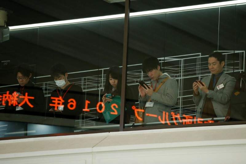 Visitors use their mobile phones before a ceremony marking the end of trading in 2016 at the Tokyo Stock Exchange (TSE) in Tokyo, Japan December 30, 2016. 