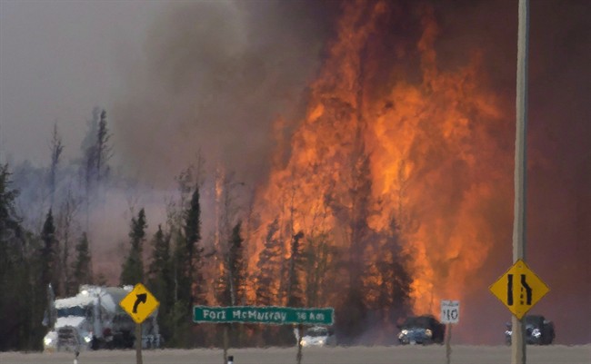Heat waves are seen as cars and trucks try and get past a wild fire 16km south of Fort McMurray on highway 63 Friday, May 6, 2016. The "beast" of a wildfire that charred Fort McMurray, Alta., was named Canada's biggest weather story of the year in an annual list compiled by the country's top meteorologists. 