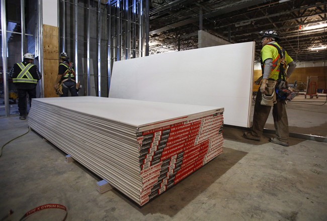 Construction workers move sheets of drywall at a building project in Calgary, Alta., Friday, Dec. 30, 2016. A decision expected later Wednesday could drive up the cost of rebuilding Fort McMurray after a wildfire swept through the northern Alberta city last spring. 