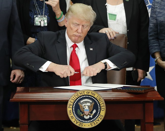 President Donald Trump takes the cap off a pen before signing executive order for immigration actions to build border wall during a visit to the Homeland Security Department in Washington, Wednesday, Jan. 25, 2017. 