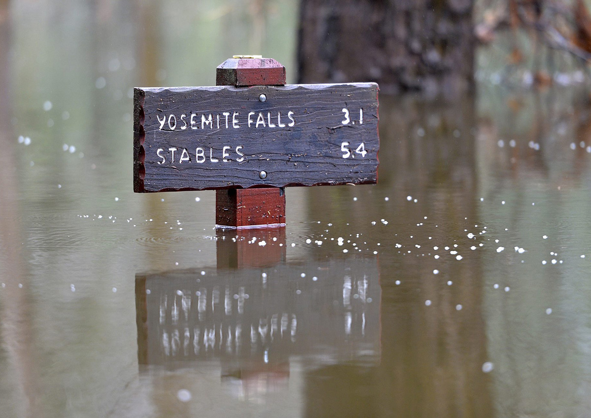 A sign is partially submerged in flood water at Yosemite National Park, Monday, Jan. 9, 2017.