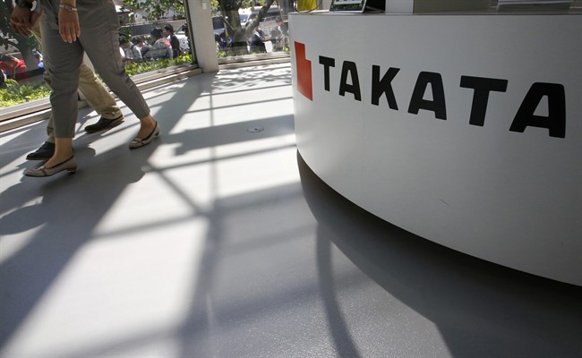 In this May 4, 2016 file photo, visitors walk by a Takata Corp. desk at an automaker's showroom in Tokyo.