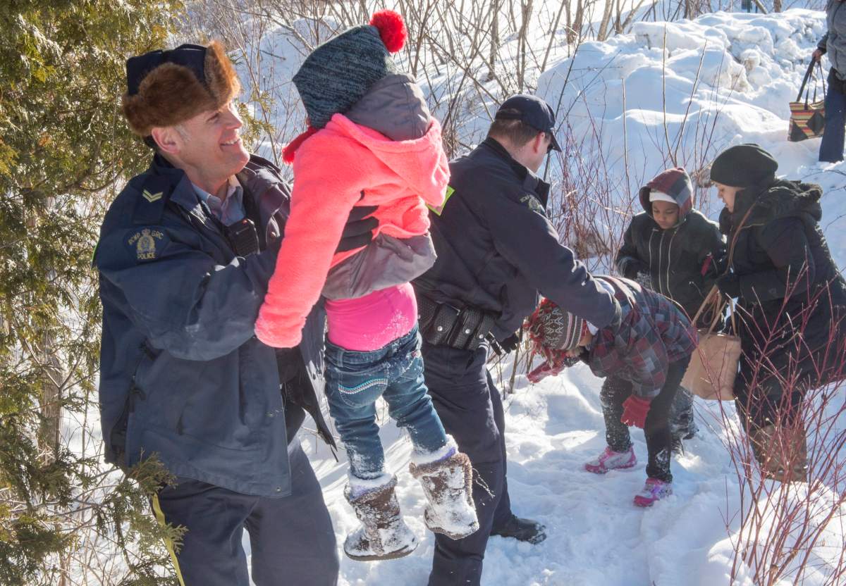 Family members from Somalia are helped into Canada by RCMP officers along the U.S.-Canada border near Hemmingford, Que., on Friday, Feb. 17, 2017.
