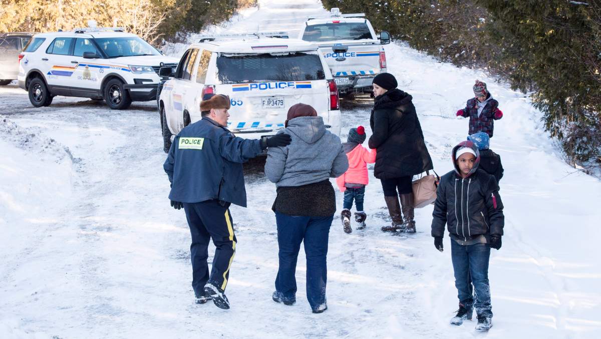 Family members from Somalia are escorted to waiting vehicles by RCMP officers following their crossing into Canada over the U.S.-Canada border near Hemmingford, Que., on Friday, February 17, 2017. A number of refugee claimants are braving the elements to illicitly enter Canada. 