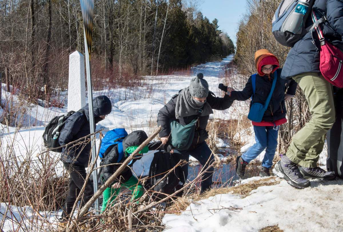 A family of asylum claimants walks across the border into Canada from the United States in February 2017.