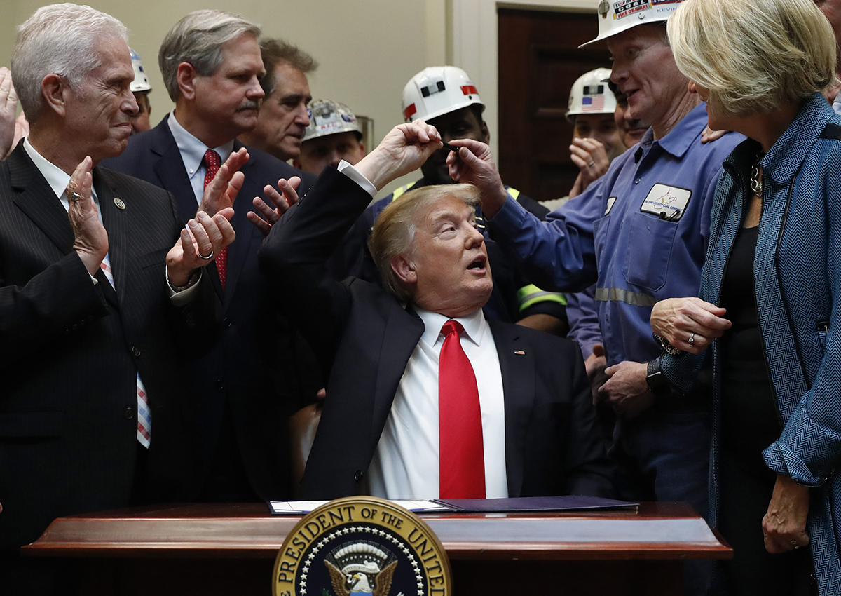 President Donald Trump hands the pen he used to sign H.J. Res. 38 to Kevin Hughes, General Manager, Murray Energy Corporation, second from right, in the Roosevelt Room of the White House in Washington, Thursday, Feb. 16, 2017. 