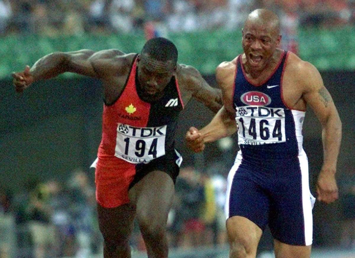 Maurice Greene of the United States, right, crosses the finish line to win the Gold medal in the Men's 100 meters ahead of Canada's Bruny Surin, left, who took silver, at the seventh World Track and Field Championships in Seville's Olympic Stadium, Sunday Aug. 22, 1999. Associated Press Photo/Michael Probst