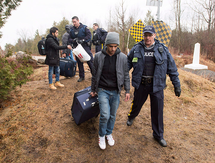 Asylum seekers, claiming to be from Yemen, are arrested by RCMP officers after crossing the border from New York into Canada on Wednesday, March 8, 2017 in Hemmingford, Quebec. 