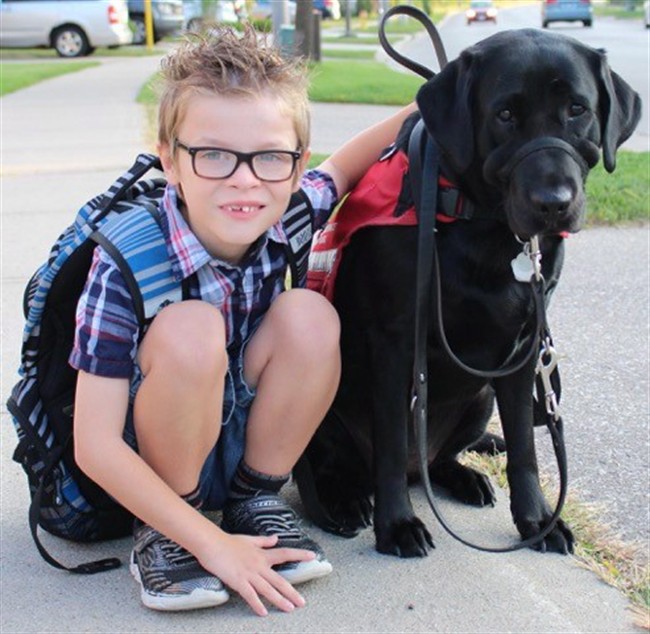 Kenner Fee poses for a photo with his service dog Ivy in this undated handout photo. An Ontario family has gone to the province's human rights tribunal to fight for their autistic son's right to bring his service animal into class.