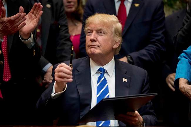 In this Monday, March 27, 2017, file photo, President Donald Trump holds up a pen he used to sign one of various bills in the Roosevelt Room of the White House in Washington. 