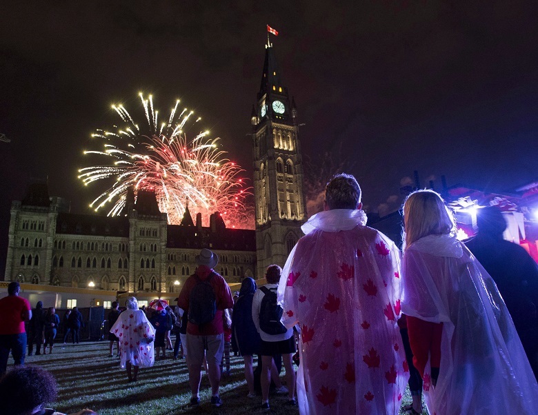 People watch fireworks as they explode behind the Peace Tower during Canada Day celebrations on Parliament Hill on Friday, July 1, 2016 in Ottawa. THE CANADIAN PRESS/Justin Tang