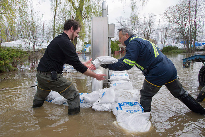 Volunteers place sandbags around an electrical panel in the town of Hudson, Que., west of Montreal, Monday, May 8, 2017, following flooding in the region.