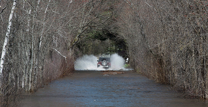 A vehicle drives on a flooded street in Fredericton, N.B., on Sunday, May 7, 2017.