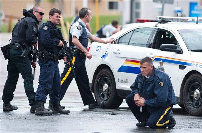 Police keep watch on a house as they search for a heavily armed gunman following the shooting of three Mounties in Moncton, N.B., on June 5, 2014.
