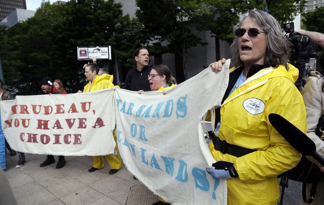 A small group of demonstrators protesting Canada’s Trans Mountain Pipeline expansion chant as Canada Prime Minister Justin Trudeau leaves a hotel steps away following a meeting Thursday, May 18, 2017, in Seattle.