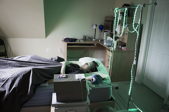 Rachael in her bedroom using green light therapy to help with the pain.