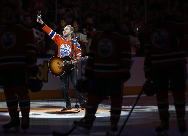 Canadian country singer Brett Kissel holds his faulty microphone asking the crowd to sing the "Star-Spangled Banner" before the start of the Anaheim Ducks and the Edmonton Oilers NHL hockey round two playoff hockey game in Edmonton, Sunday, April 30, 2017.