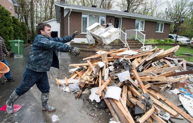In this 2017 file photo, David Samuelson throws debris from his flooded house onto a pile on his driveway in the Pierrefonds borough of Montreal. 