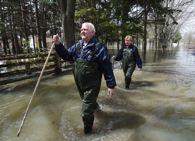 Paul and Suzanne Diamond walk through the floodwaters from Lac-Saint-Pierre to check on their cottage Saturday, May 13, 2017 in Yamachiche, Que.