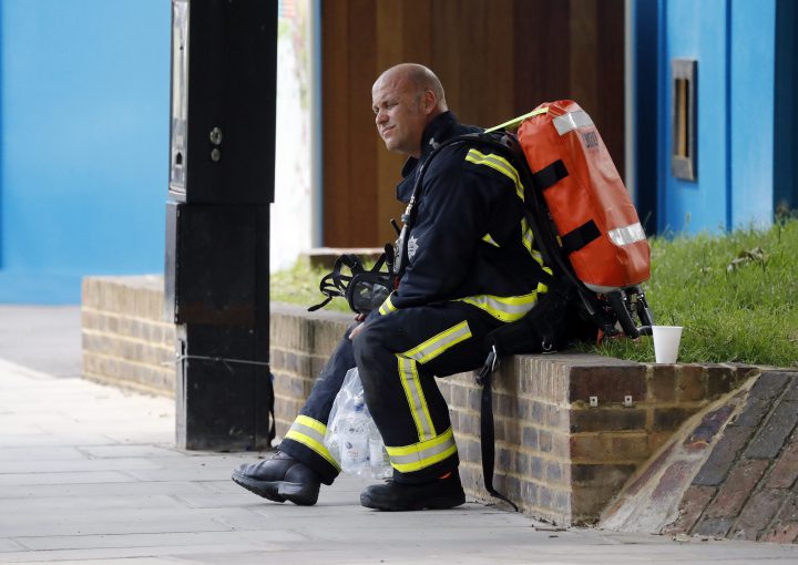 A fire officer rests near the high-rise apartment building where a massive fire raged overnight in London.
