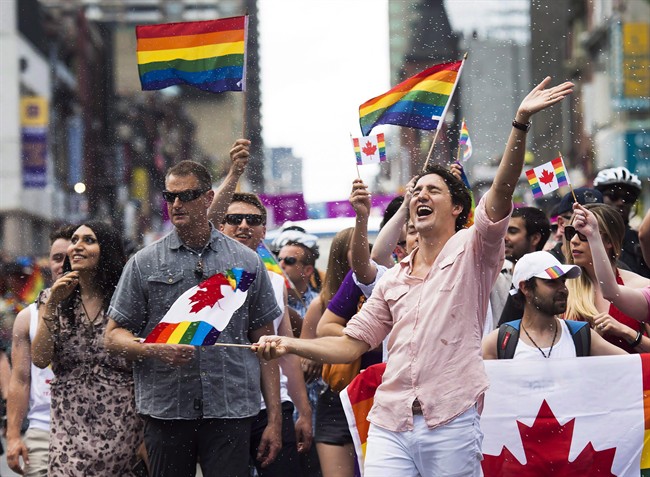 Prime Minister Justin Trudeau is splashed with water as he waves a flag at the annual Pride Parade in Toronto on Sunday, July 3, 2016.