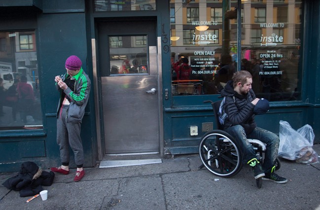 A woman, left, prepares to inject herself with an unknown substance outside Insite, the supervised consumption site, in the Downtown Eastside of Vancouver on Feb. 21, 2017.