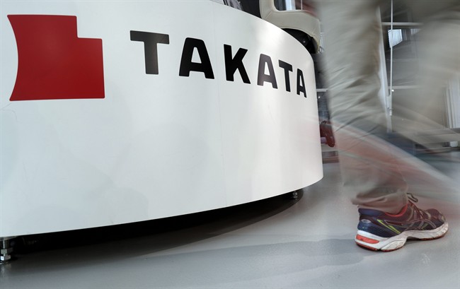 In this May 10, 2017 photo, a visitor walks past the logo of Takata Corp. at a Toyota showroom in Tokyo. 